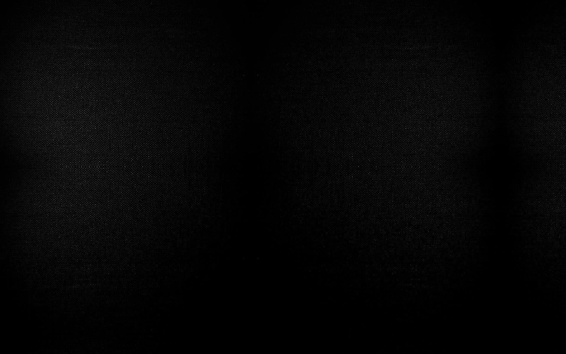 A dark canvas backdrop with two soft pools of light near the top, the rest of the frame falling into black.