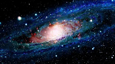 Colour-boosted view of a spiral galaxy, its white-pink core burning inside deep blue arms flecked with red star knots on a star-dusted black field.