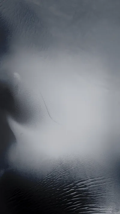 Light spreads through a sheet of frosted glass, blooming white at the centre and cooling to blue-grey where fine ripples run along the bottom.
