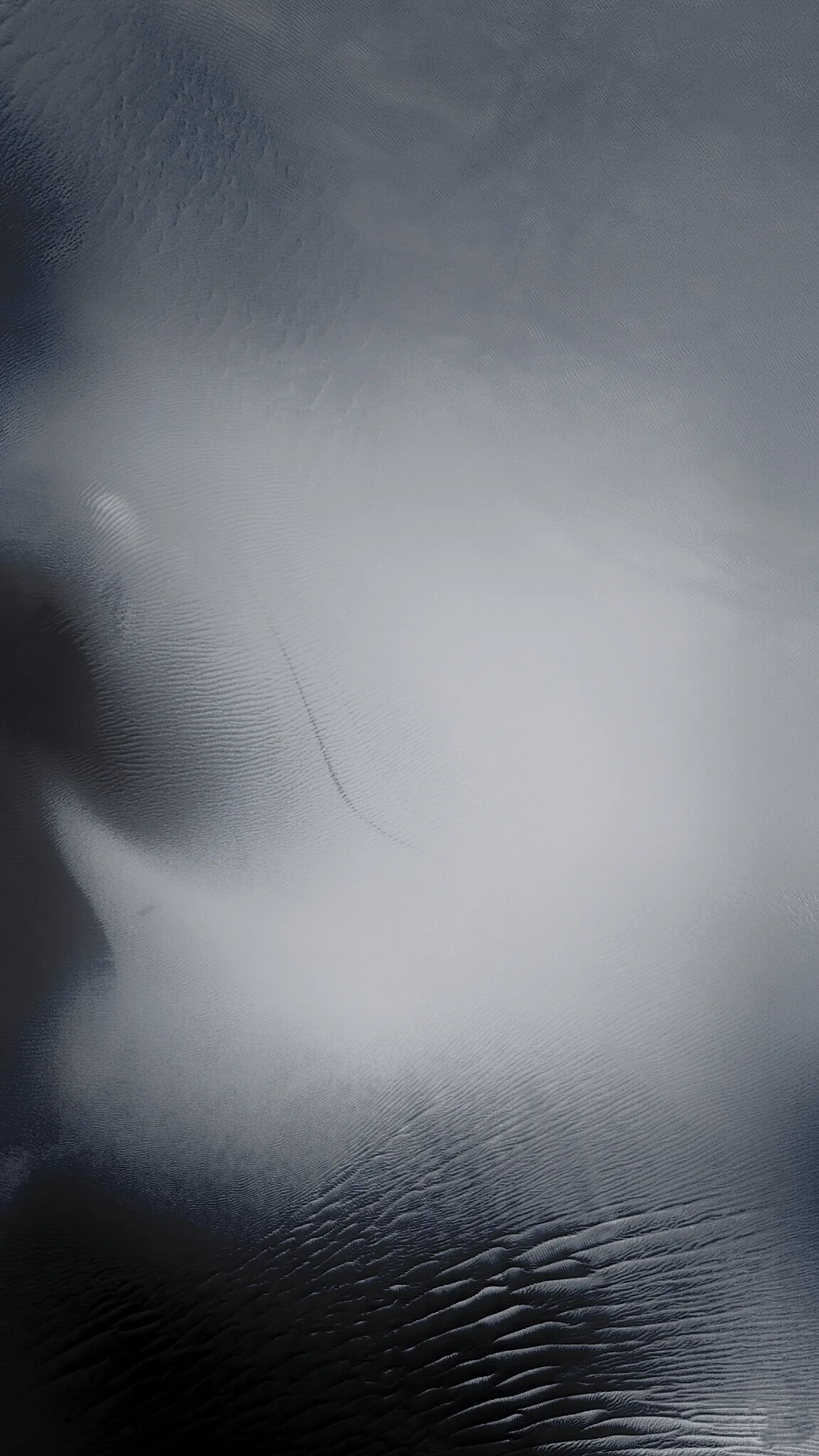 Light spreads through a sheet of frosted glass, blooming white at the centre and cooling to blue-grey where fine ripples run along the bottom.