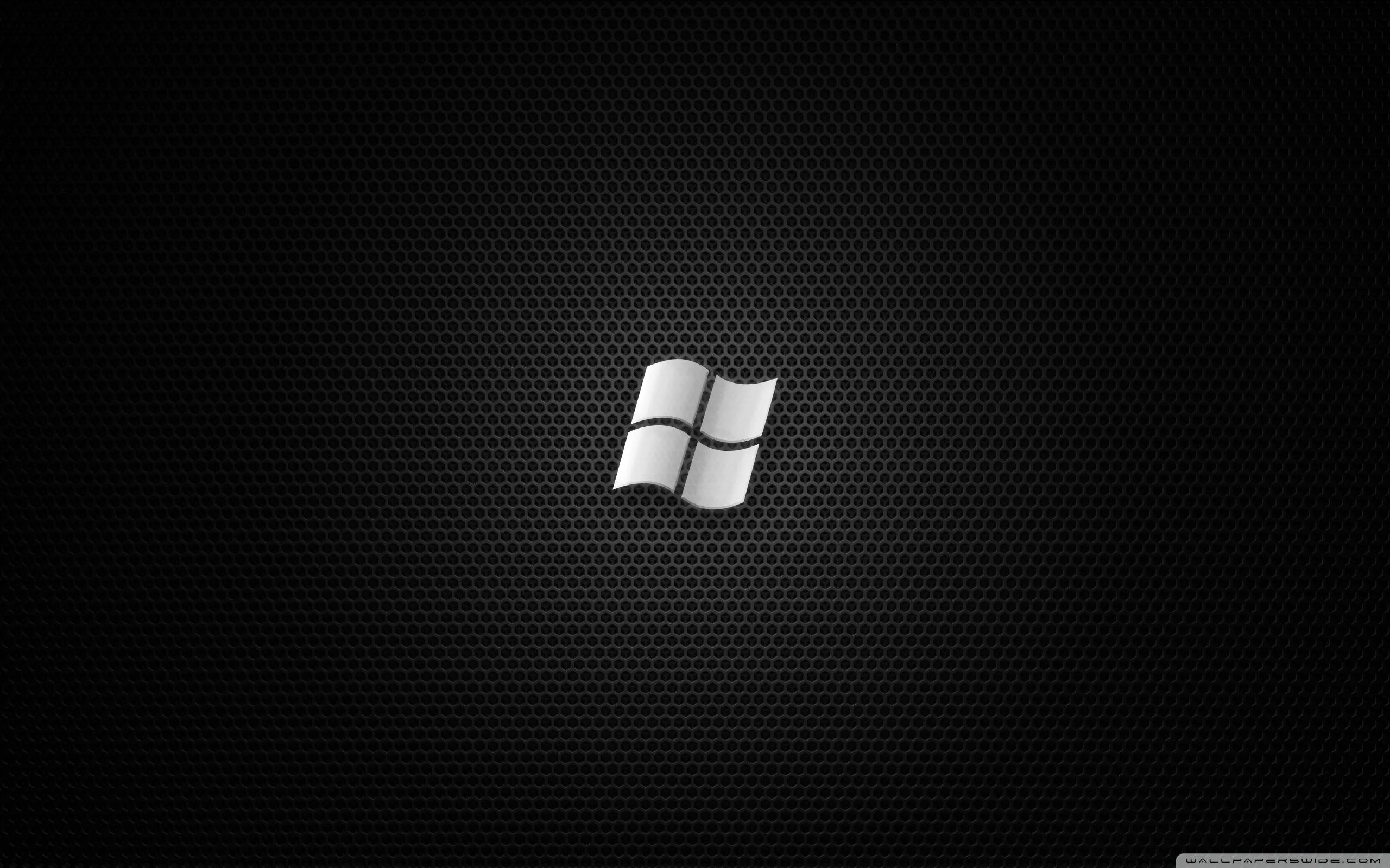 The Windows flag sits small and bright at centre on a dark honeycomb weave, the surrounding texture dropping away into shadow.