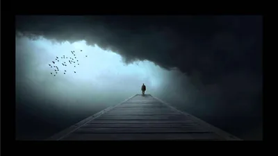 Black letterbox bars frame a walker heading up a long boardwalk into a ceiling of storm cloud, a bird flock scattering at the left.