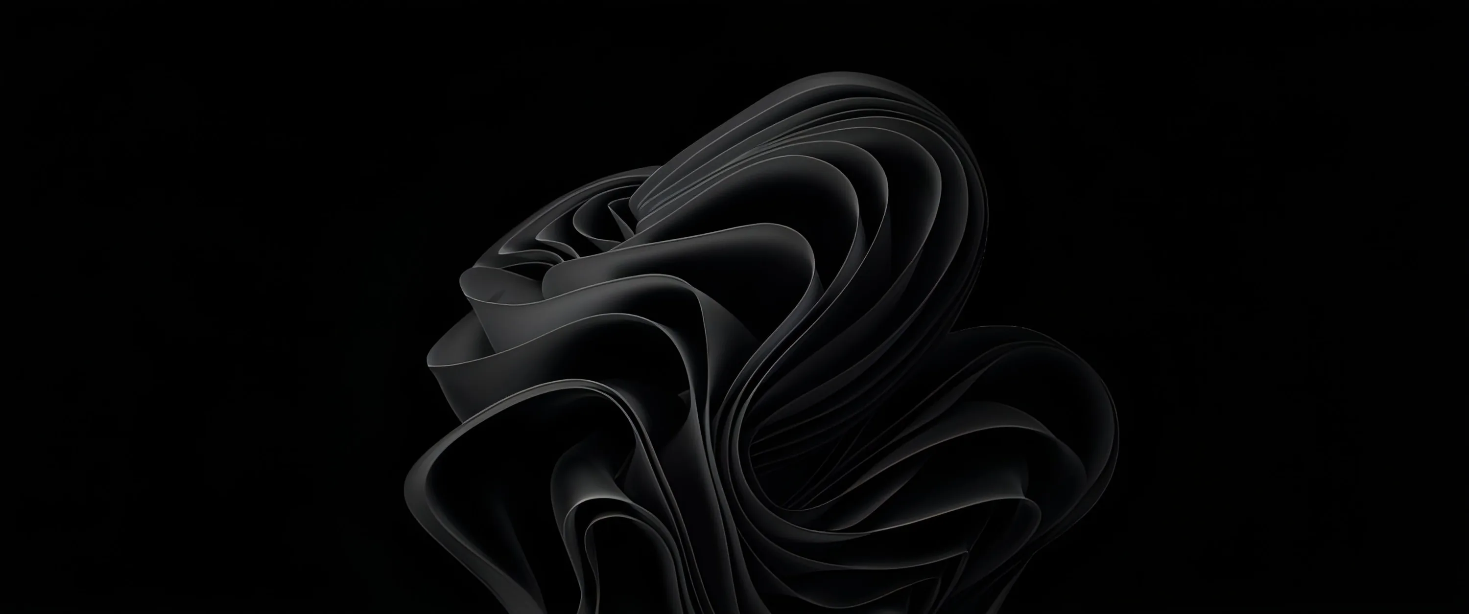 The Windows 11 bloom shape rendered as layered dark ribbons curling in on themselves, set slightly left of centre with the rest of the ultrawide frame in black.