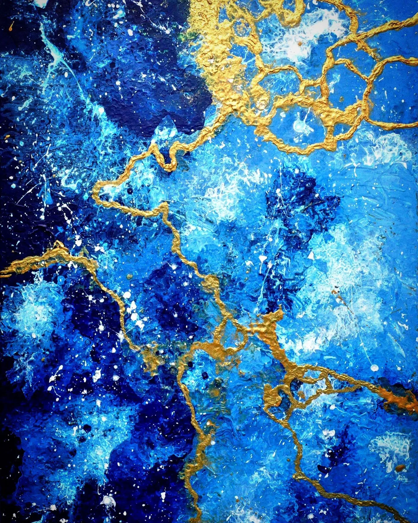 Layers of sapphire and sky blue paint are flecked with white spray, with thick crackled gold veins running from the top right corner down through the centre.