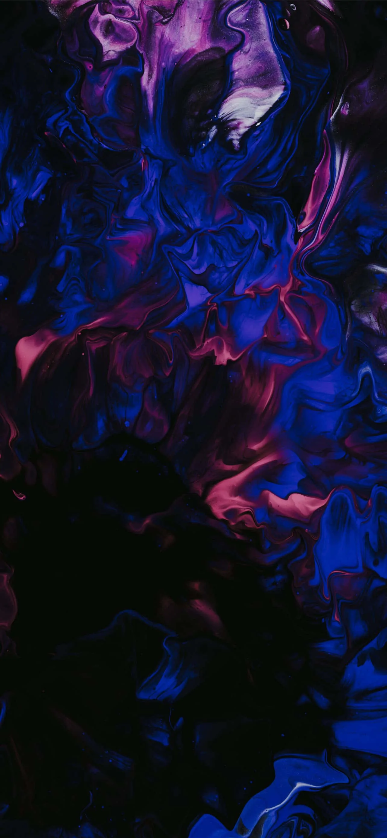 Ink-like clouds of blue and magenta churn together against black, brightest through the middle and dissolving into darkness at the edges.