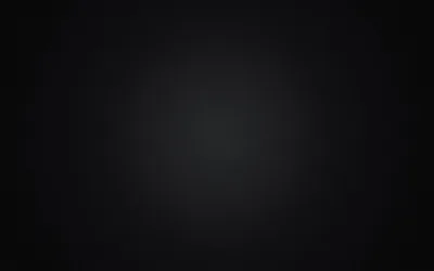 A wide diffuse pool of charcoal grey sits slightly above centre and falls away to deep black at every corner — a clean backdrop with nothing competing for attention.