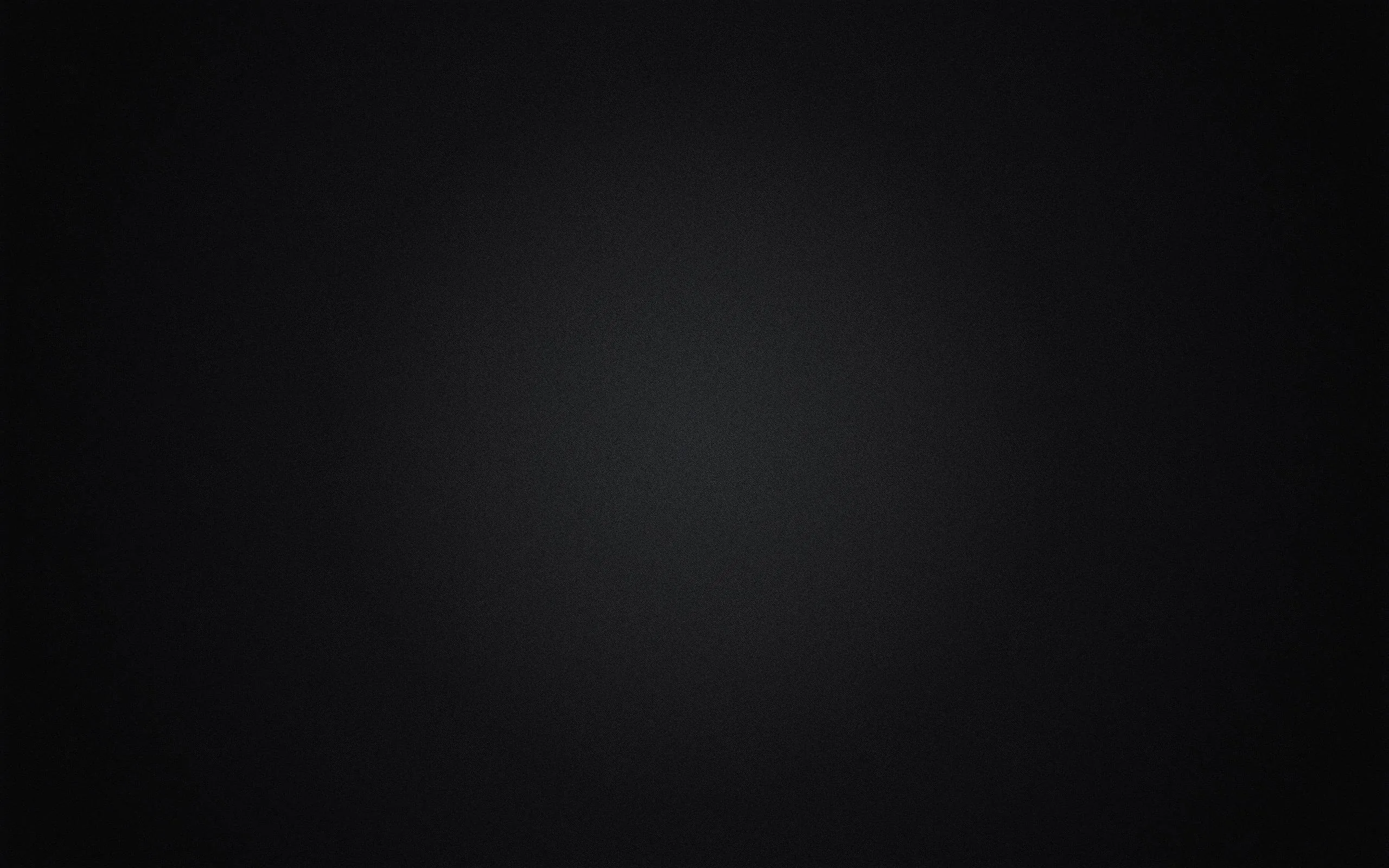 A wide diffuse pool of charcoal grey sits slightly above centre and falls away to deep black at every corner — a clean backdrop with nothing competing for attention.