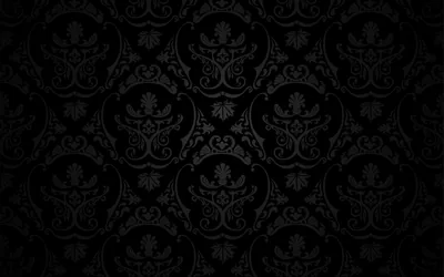 An ornate damask repeat in charcoal on black, the motif visible only where the surface catches light.