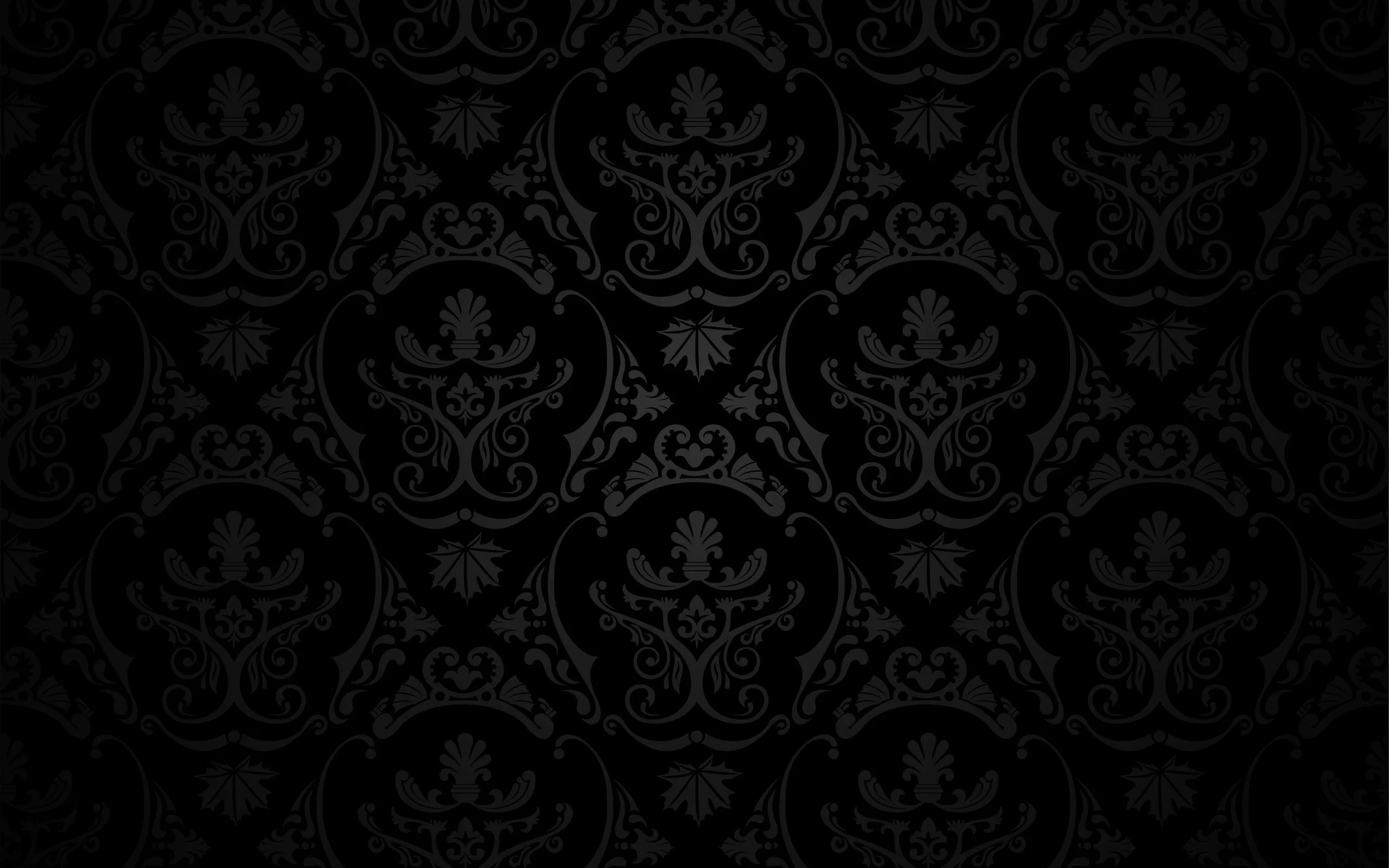 An ornate damask repeat in charcoal on black, the motif visible only where the surface catches light.