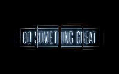 Three lit panels spell out a short phrase in cool white neon, the surrounding wall dropping straight to black.