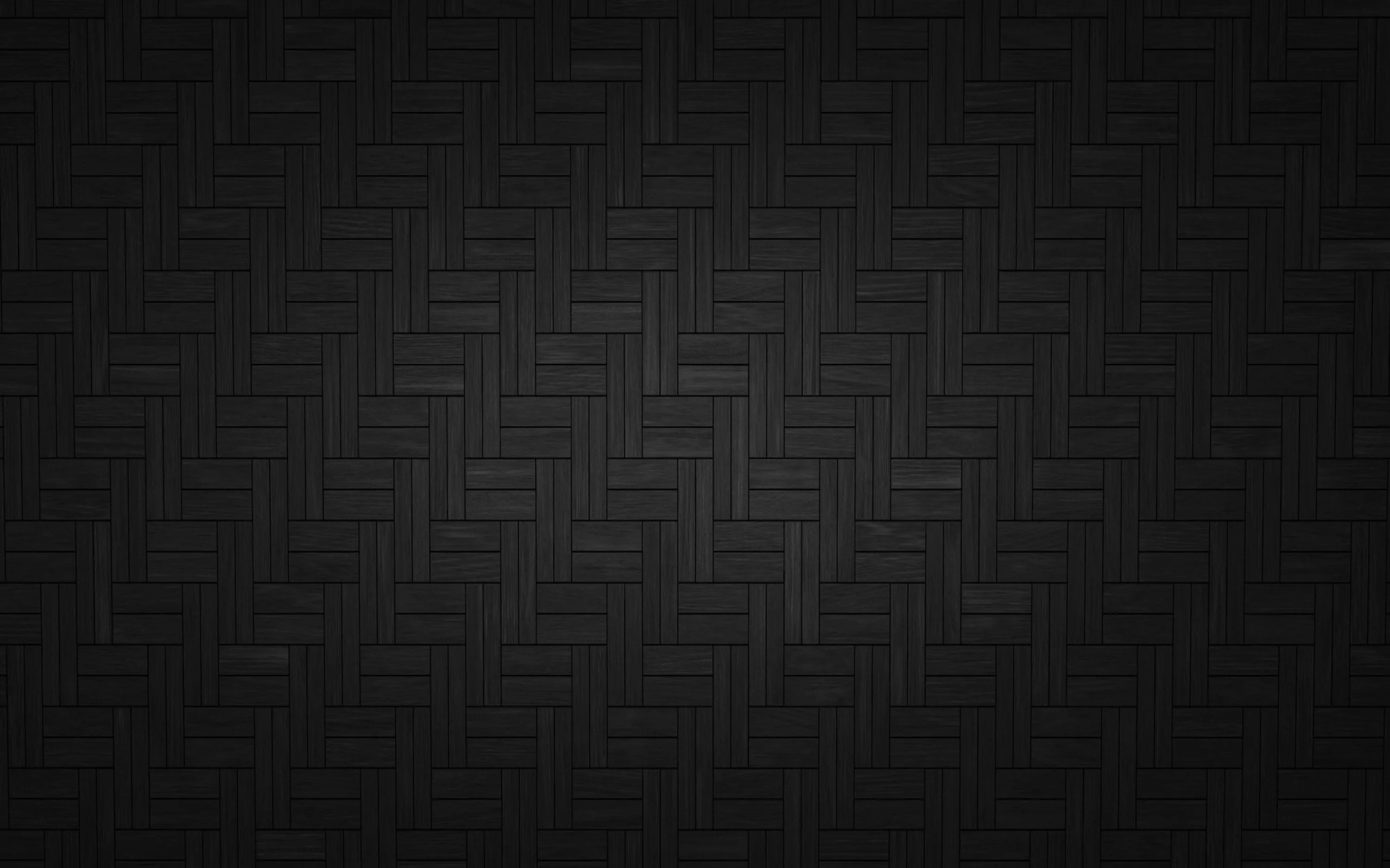 Charcoal tiles laid in a herringbone weave fill the frame, a soft vignette darkening all four corners around a lighter centre.
