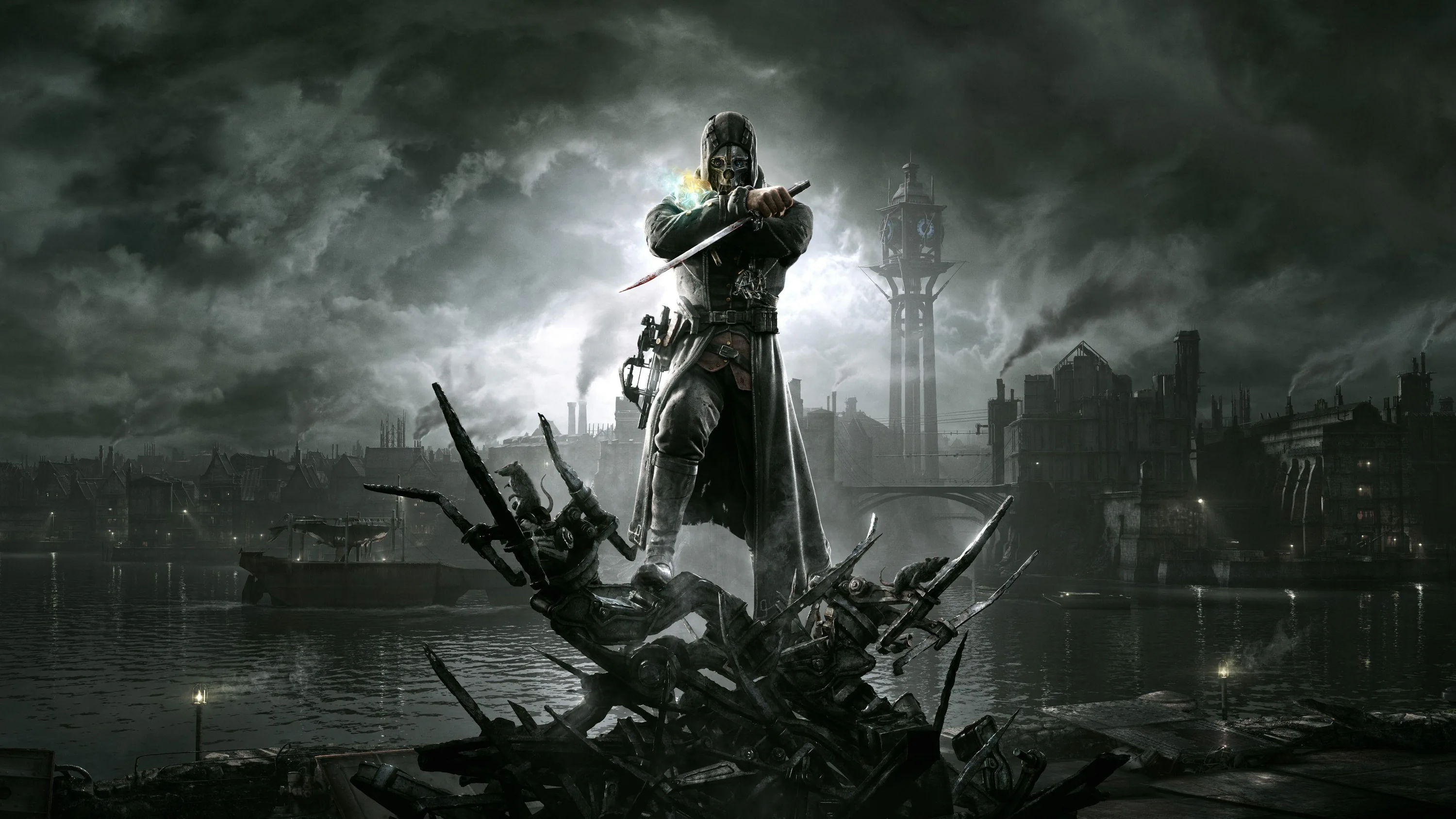 A masked figure in a long coat stands on a heap of broken timber, a lit tower and smoking rooftops behind under heavy cloud.
