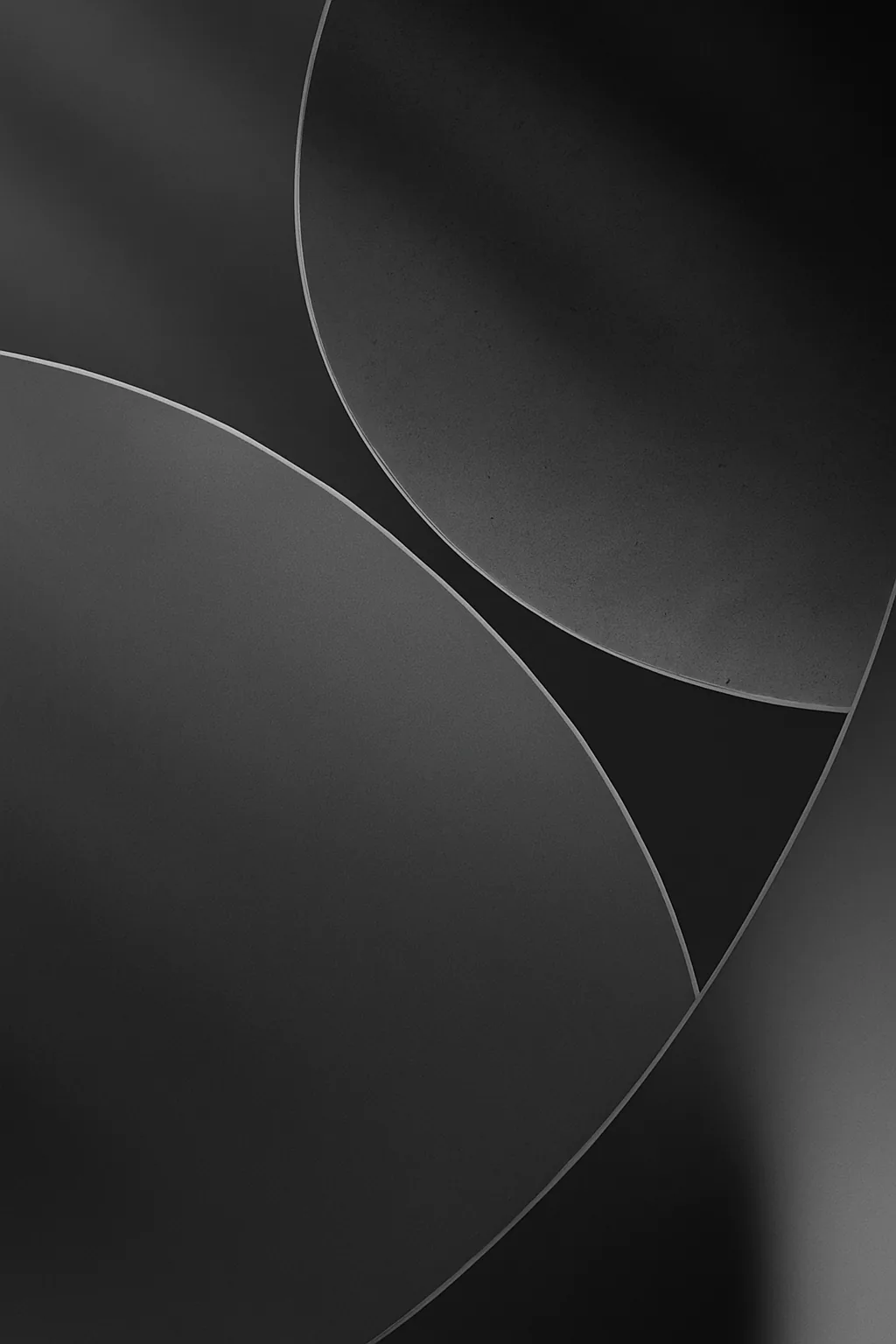 Two large circles cross in soft grey gradients on black, leaving a sharp wedge where they meet.