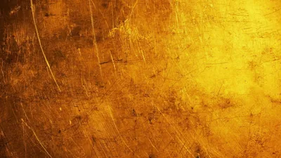 An aged sheet of gold metal covered in fine scratches, light massing in the upper right while the lower left holds a deep amber shadow.