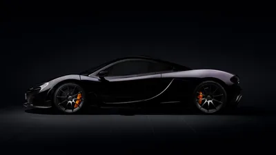The P1 in pure side view against an unlit backdrop, orange brake calipers and a thin rim of light along the roof the only detail.