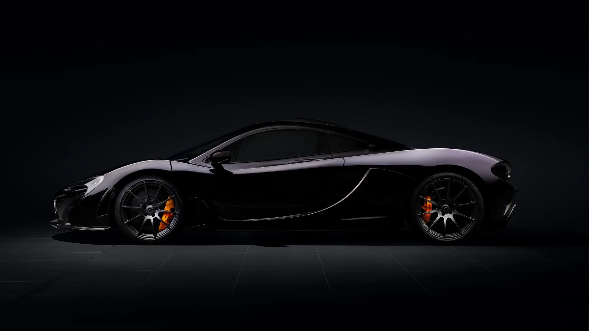 The P1 in pure side view against an unlit backdrop, orange brake calipers and a thin rim of light along the roof the only detail.