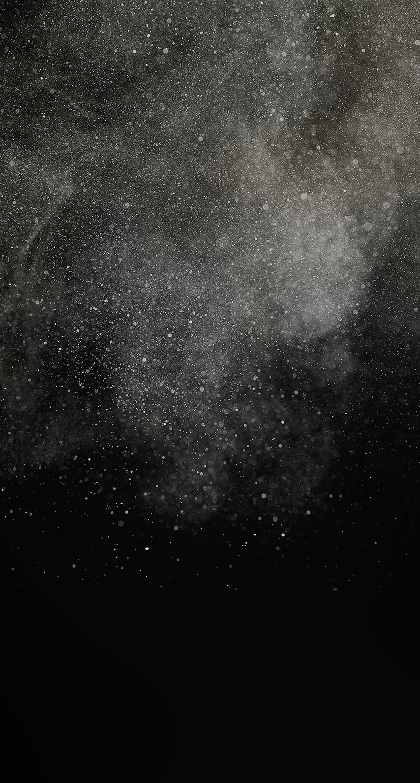A burst of pale grey powder hangs in the upper frame, individual specks scattering out before everything drops to black.