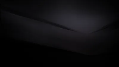 Two flat charcoal surfaces meet in a soft diagonal seam, the light just catching the fold where they join.