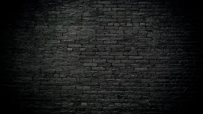 Painted black brickwork fills the frame, a soft glow across the middle rows fading to unlit corners on every side.