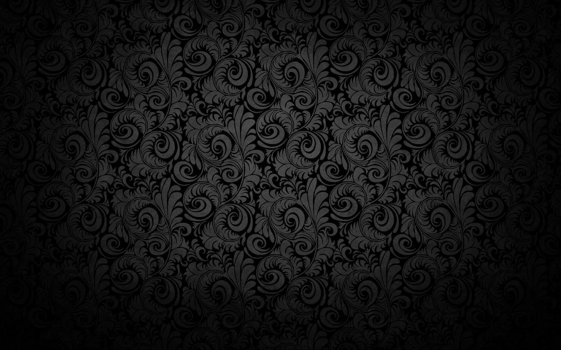 A dense baroque scroll pattern repeats over a black ground, brightest at the centre and vignetting at the corners.