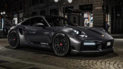 The 911 stands three-quarter on a European street after dark, mesh wheels and red calipers lit by shop windows behind it.