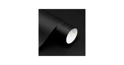 A part-unrolled sheet of matte black adhesive paper on white, the flat side showing its texture and the roll's white core visible at the end.