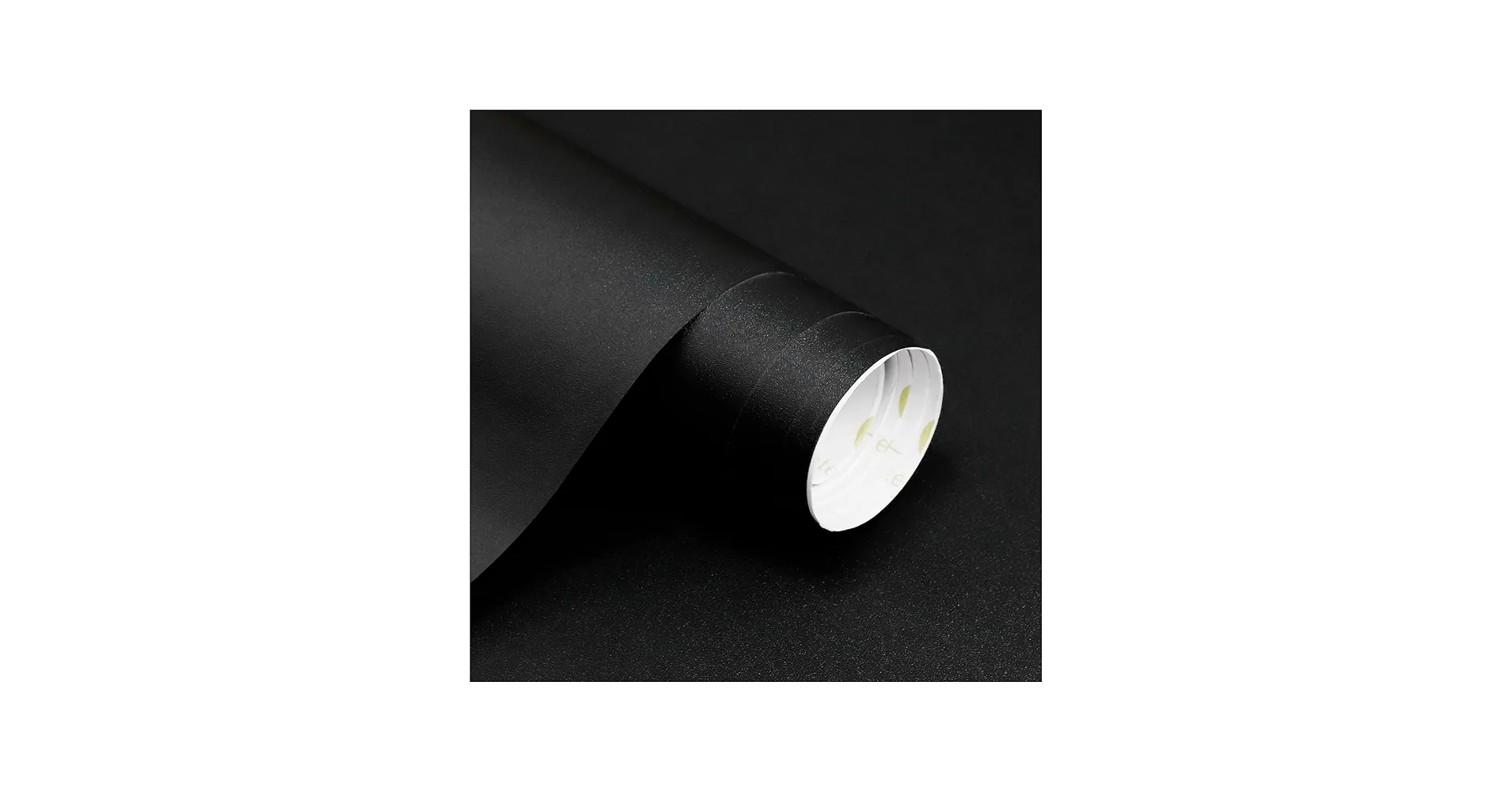 A part-unrolled sheet of matte black adhesive paper on white, the flat side showing its texture and the roll's white core visible at the end.
