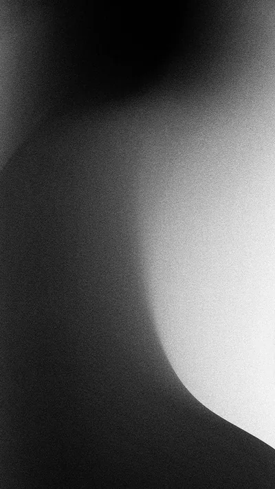 A grainy monochrome study: white light bends along the right edge while the left two-thirds fall to charcoal, leaving most of the frame dark.