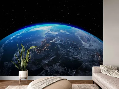 A room-scale photo of the orbital Earth mural behind a sofa and potted plant — a preview of the print on an actual wall rather than a screen.