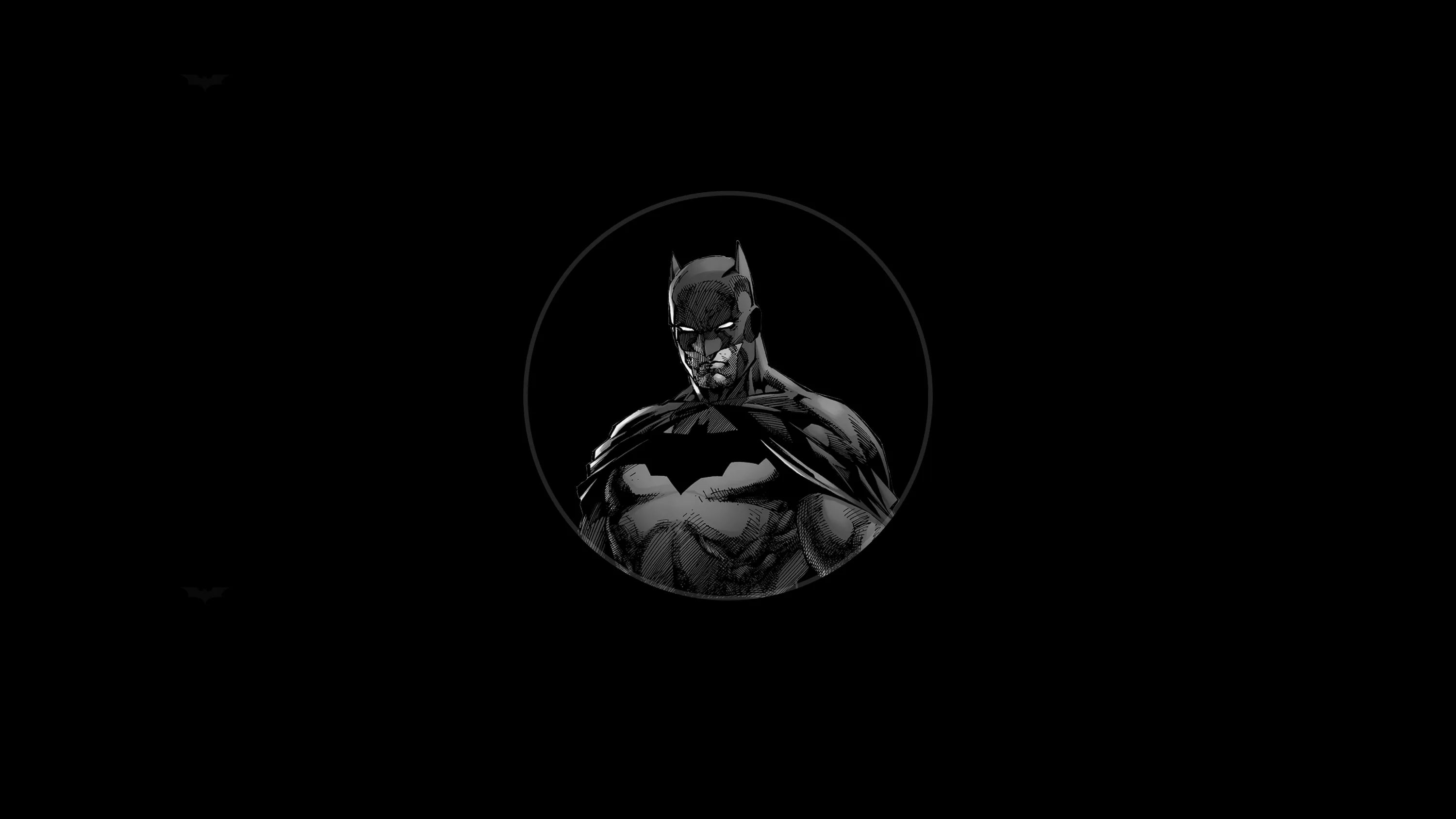 A caped figure stands inside a small lit circle at the centre of the frame with nothing else around it.