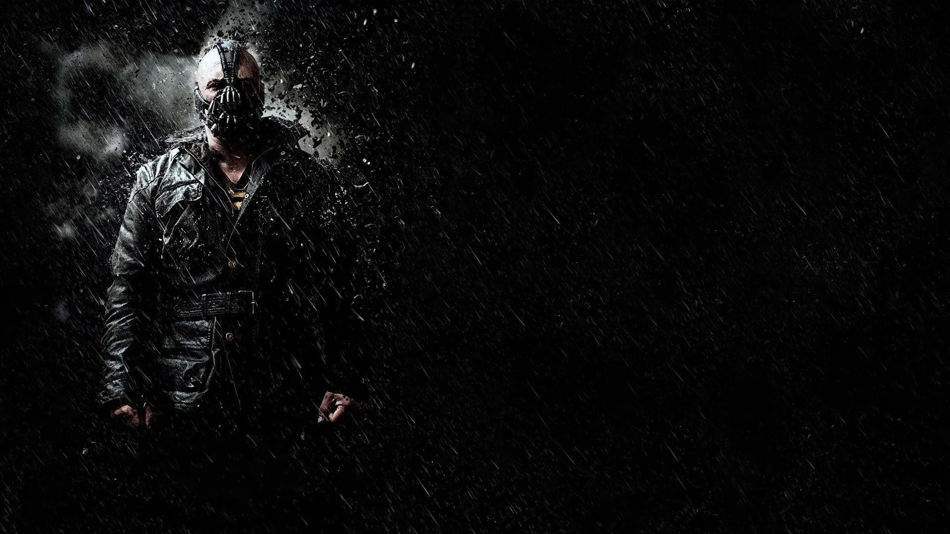 Bane stands to the left in his heavy coat and mask as rain streaks across the frame, the whole right half left dark and open.