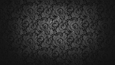 A repeating damask scroll covers a charcoal wall in low relief, lit from the centre so the pattern sinks into black around all four edges.