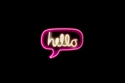 The word hello in warm white cursive sits inside a pink neon speech bubble, everything else true black — an OLED lock screen that keeps the area above clear for the clock.