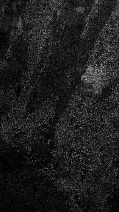 Coarse dark stone fills the tall frame with faint diagonal scuffs running down it, one pale scratch breaking the surface near the middle.