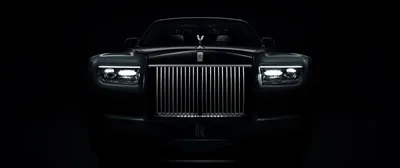 Shot dead-on and close, the tall chrome grille and Spirit of Ecstasy catch a thin light while the bonnet and both flanks fall away into shadow.