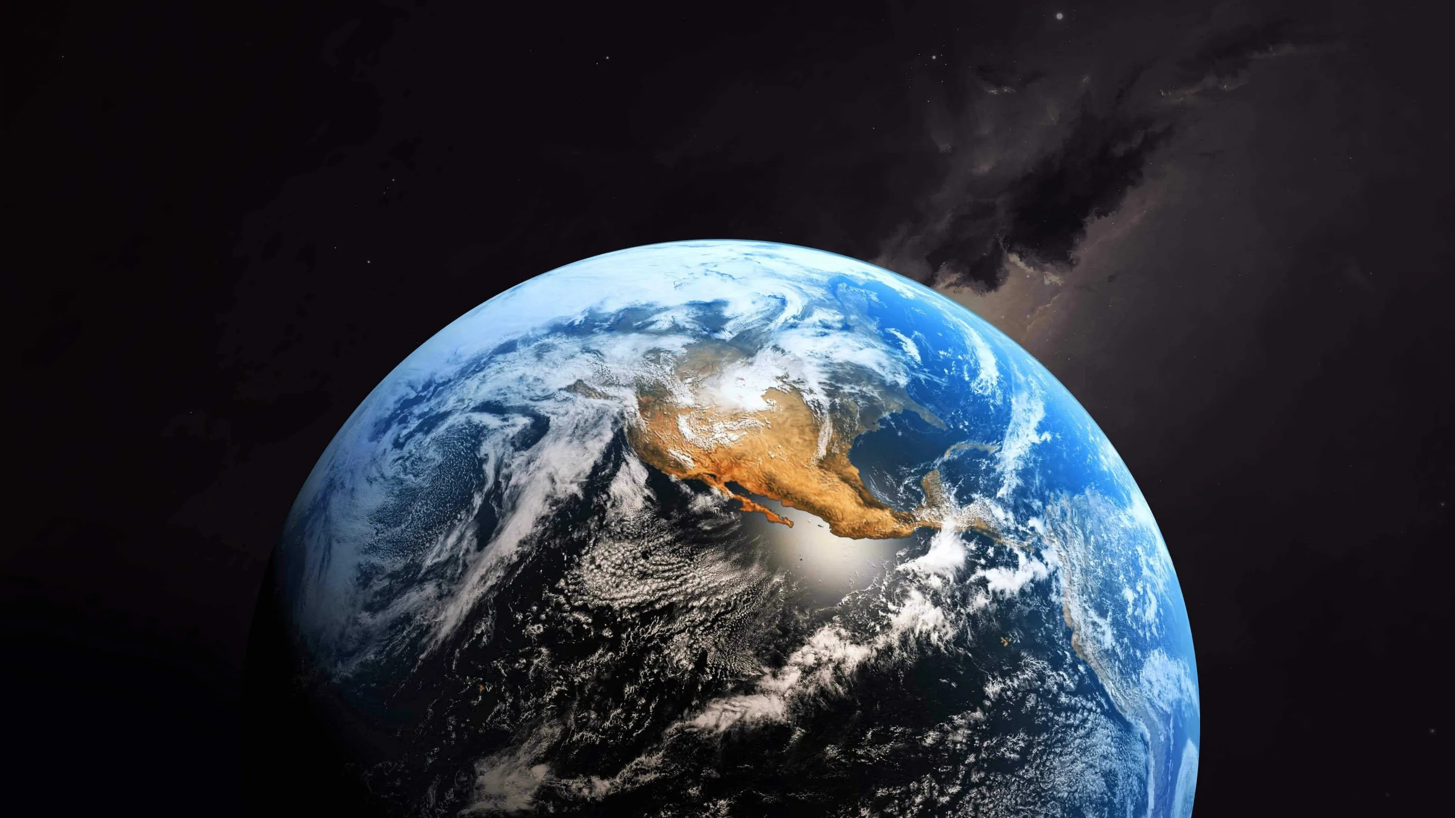 A tan landmass catches the sun at the middle of the blue globe, a dark nebula smudge crossing the upper right corner of the black sky.