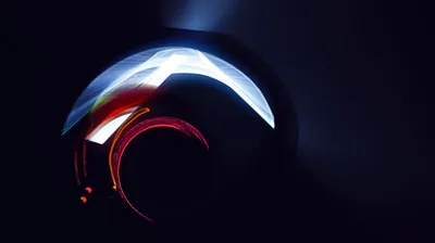 A curved reflective surface catches a bright white streak with a red edge, the rest of the object reading as near-black.