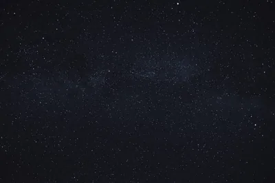 A real night exposure, mostly deep navy-black, with the Milky Way showing only as a faint dusty smear across the middle.