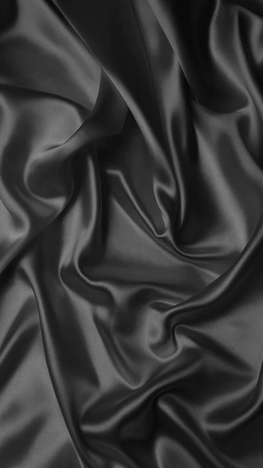 Black satin gathers into soft folds and hollows, the sheen picking out each crease while the deeper valleys go fully black.