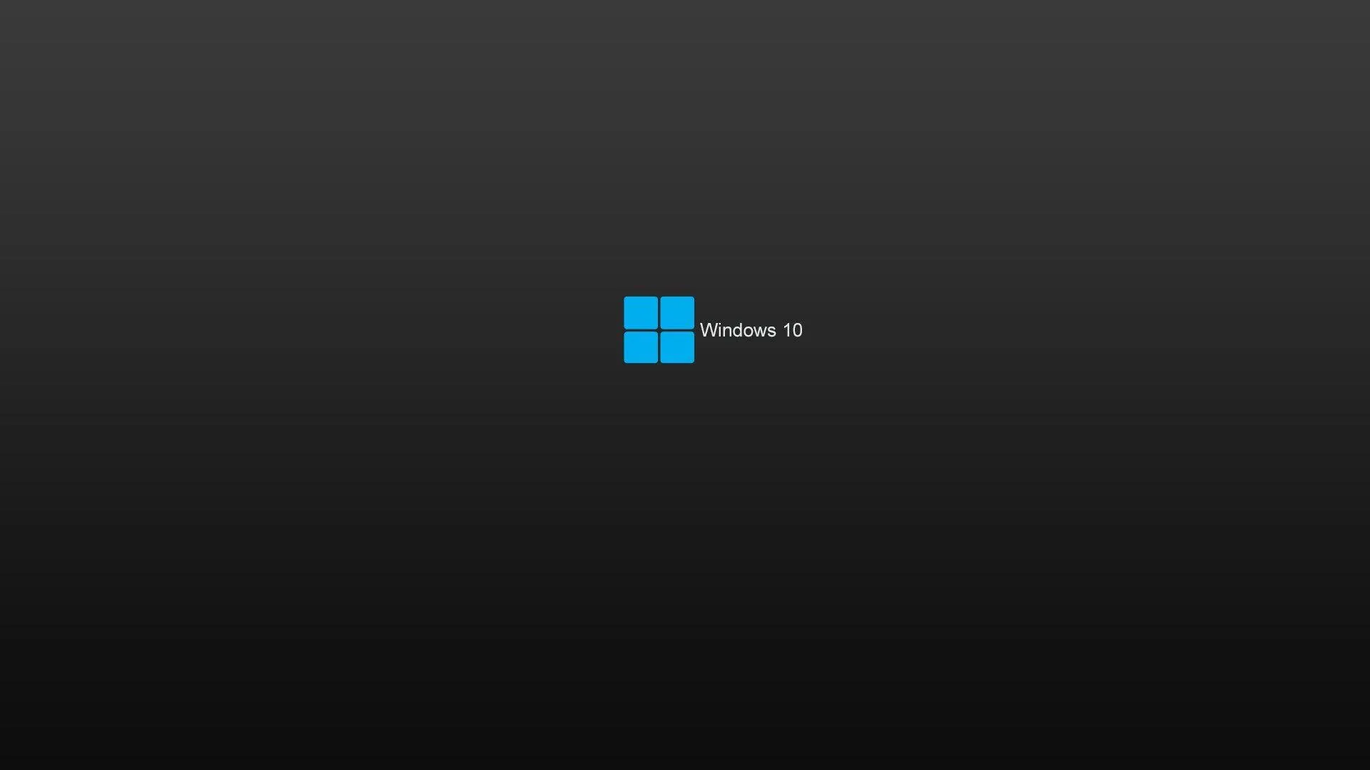 The blue Windows 11 mark with its wordmark, small and centred on a smooth dark grey gradient that darkens toward the edges.