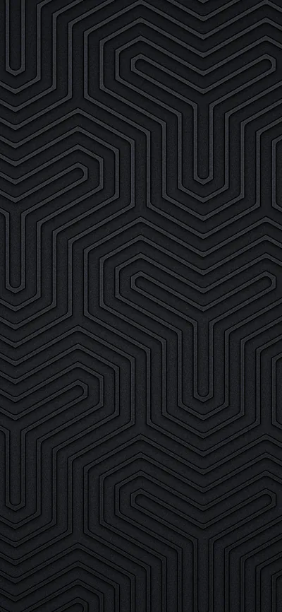 Concentric hexagonal grooves interlock like a labyrinth down the tall frame, each ridge picking up a thin highlight against matte charcoal.
