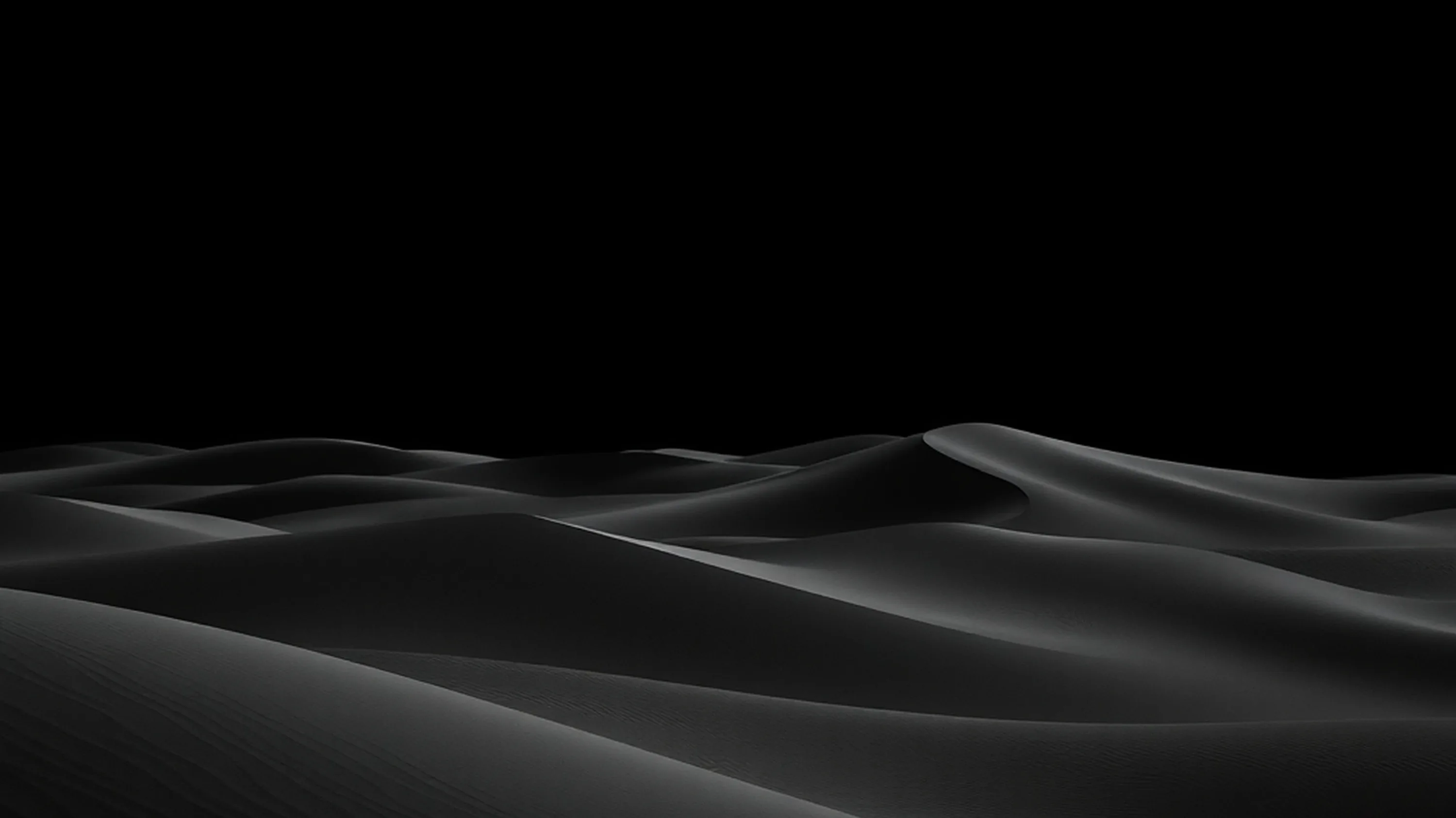 Low light rakes across a run of dunes, picking out each crest and leaving the sky above completely black.