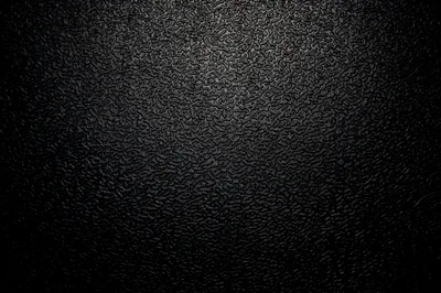 A coarse grain covers the whole surface in near-black, lit from the upper left so the pitting reads before it drops into a heavy vignette.