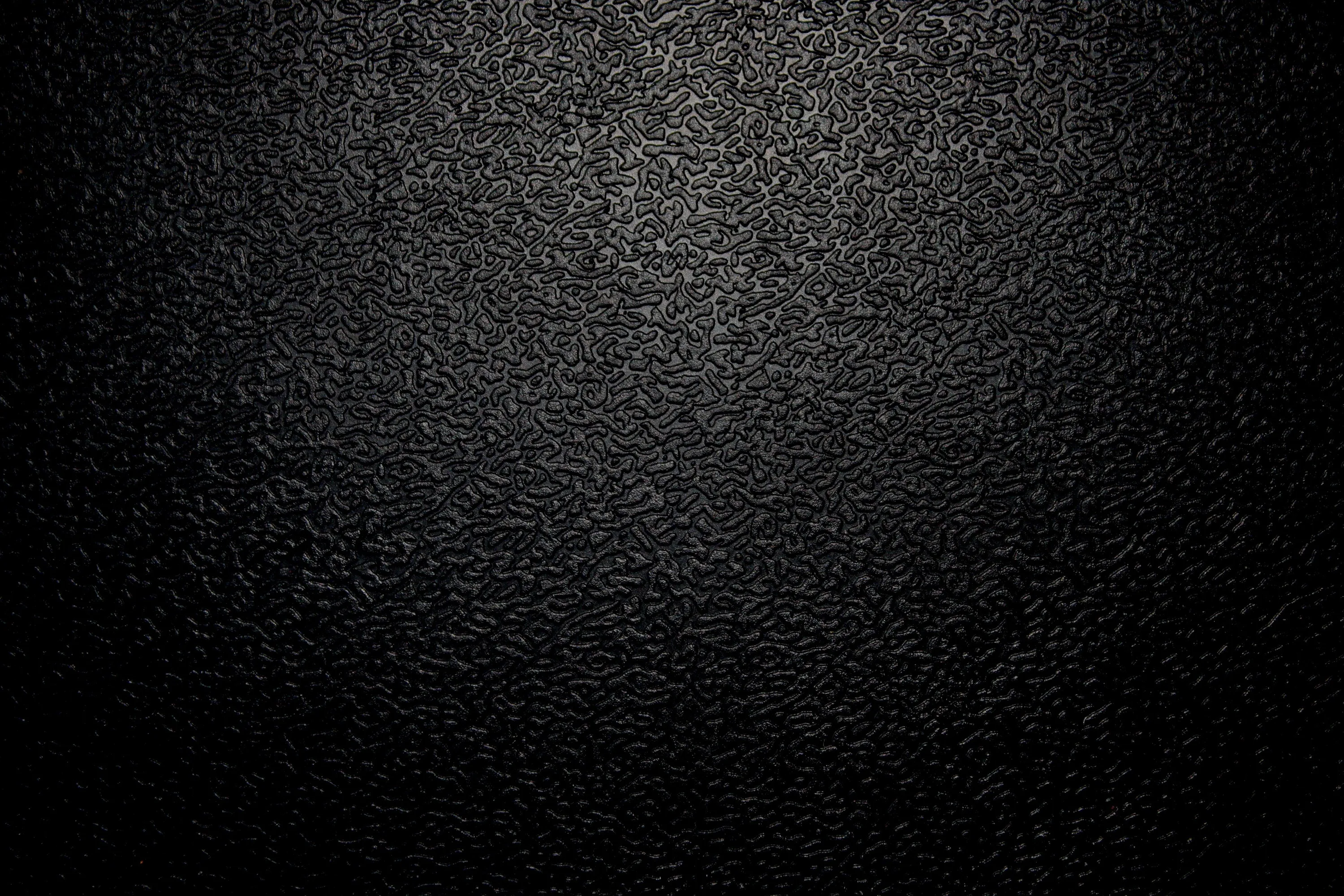 A coarse grain covers the whole surface in near-black, lit from the upper left so the pitting reads before it drops into a heavy vignette.
