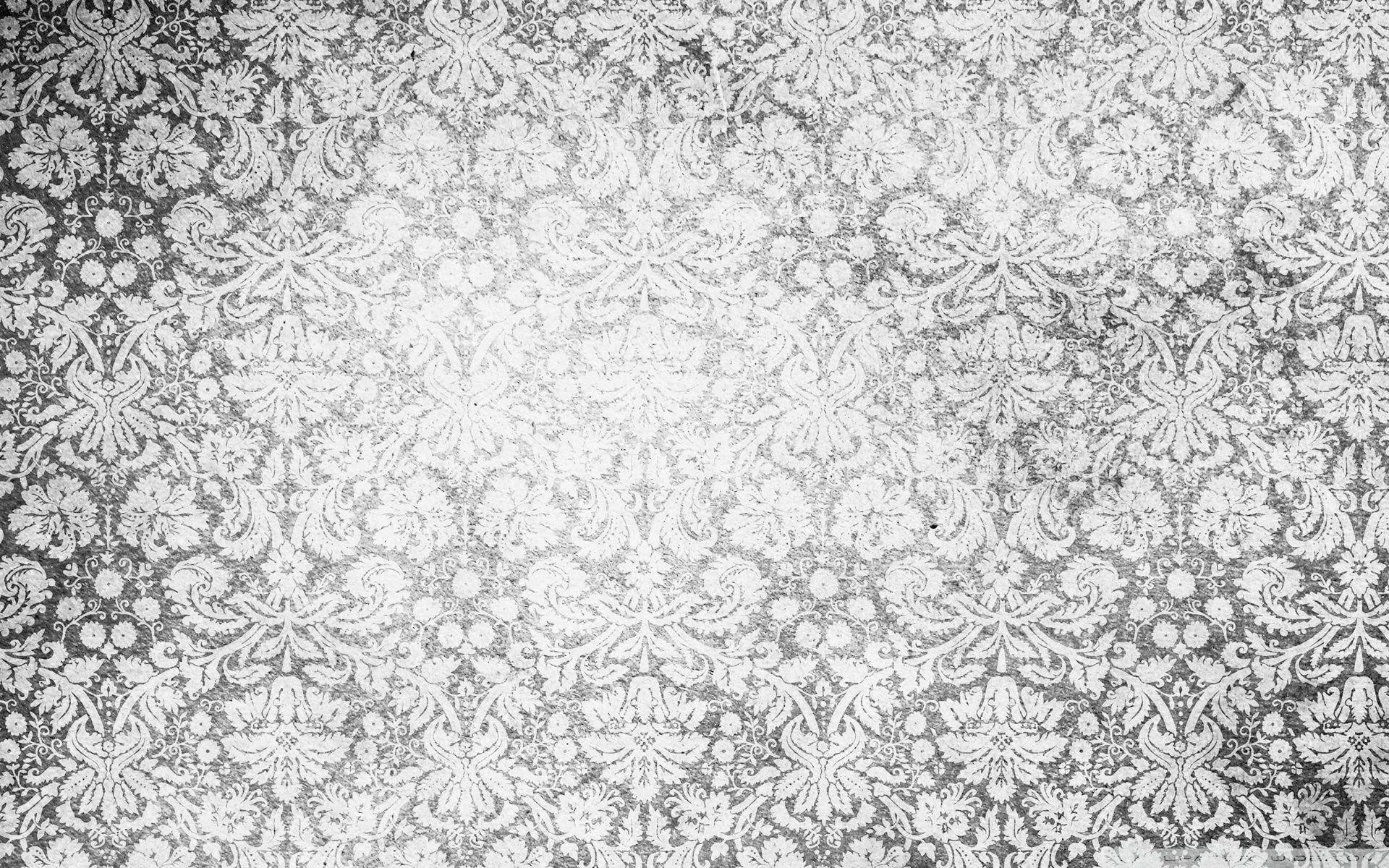 A worn damask print sits under heavy grain and light streaks, the pattern strongest in the middle and fading toward the corners.