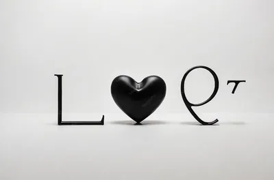 Sculpted black letters spell Love across a seamless white studio ground, a glossy heart standing in for the O, soft shadows pooling beneath each piece.