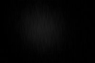 Fine vertical scratches cover a black sheet, catching just enough light near the middle to show the grain before it drops away at the corners.