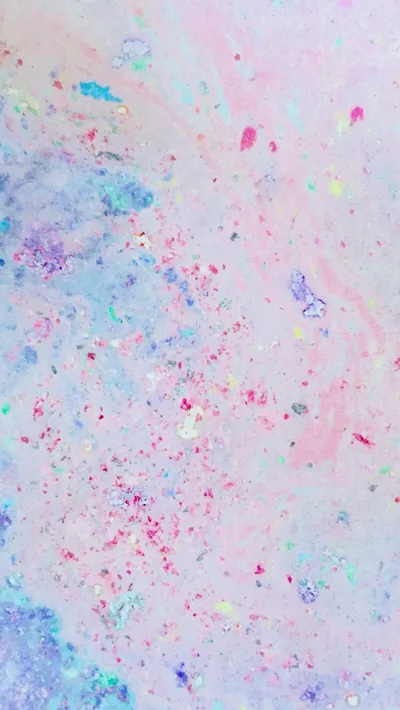 Flecks of magenta, mint and lilac scatter over a soft pink and blue marbled ground, dense in patches and sparse elsewhere.