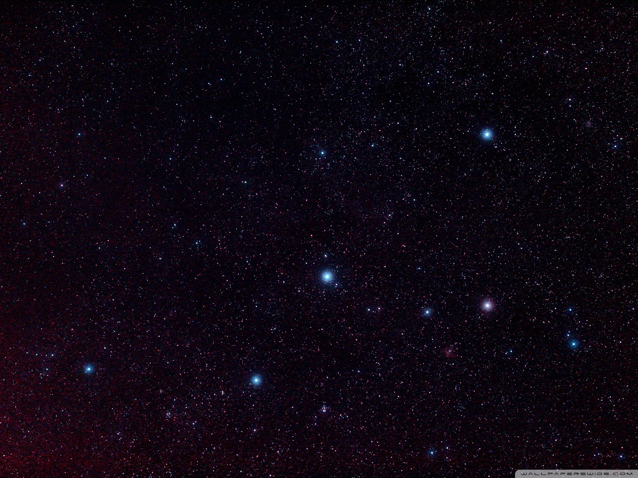 Blue and red stars scatter across a night sky washed faintly purple, a handful of brighter points catching the eye near the middle.
