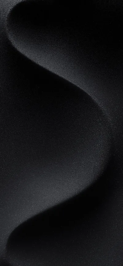 A single soft fold runs down a matte black surface, the grain of the weave showing only where the light grazes the crest.